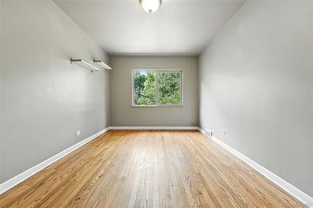 an empty room with wooden floor exposed radiator and windows