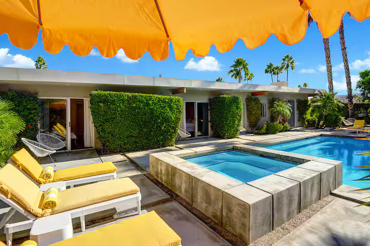 623 Desert Way Palm Springs, CA 92264 - Photo 18 of 39 a view of a white house with a large pool and a table and chairs under an umbrella