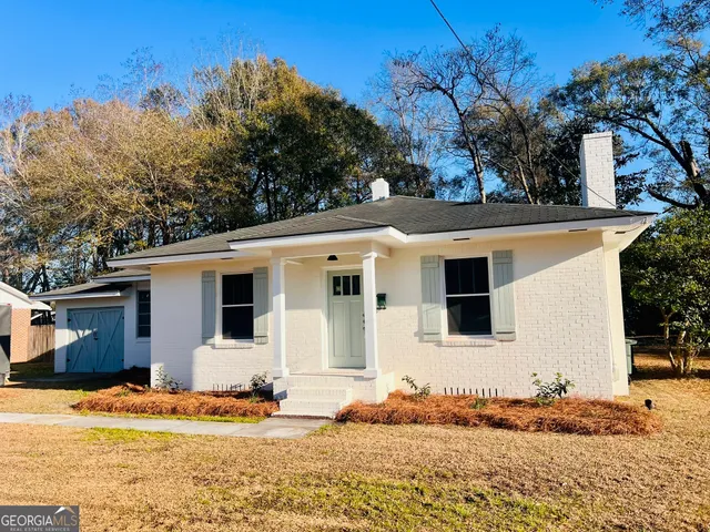 a view of a white house with a large tree