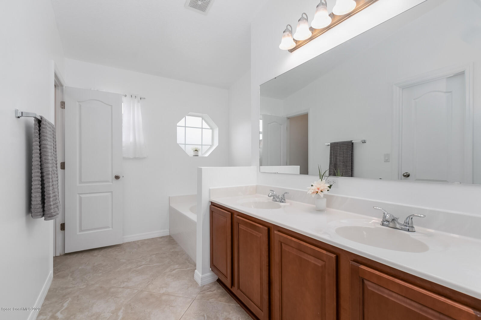 3316 Slate Street West Melbourne, FL 32904 - Photo 19 of 35 a bathroom with double vanity sinks a vanity a lamp and a mirror