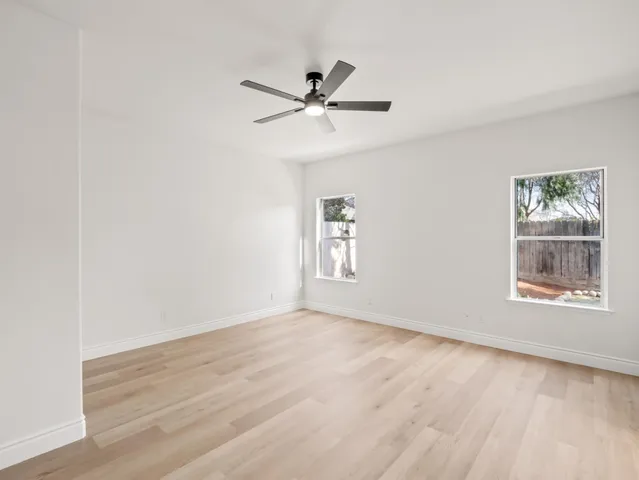 an empty room with wooden floor window and ceiling fan