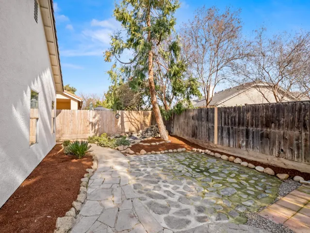 a backyard of a house with large trees and wooden fence