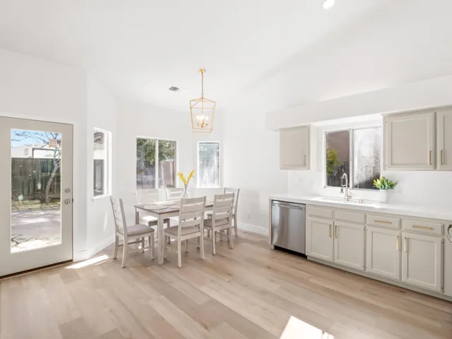 a large white kitchen with granite countertop a dining table chairs and a large window