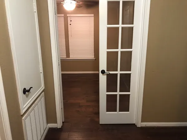 a view of an empty room with wooden floor and a window