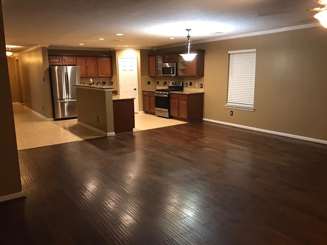 an open kitchen with wooden floor and stainless steel appliances