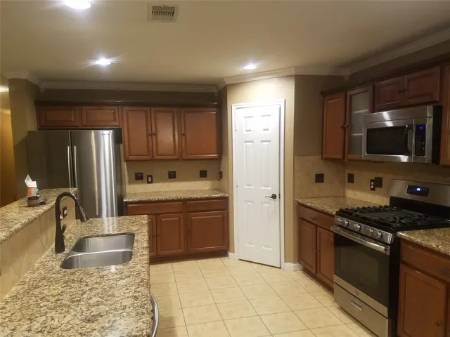 a kitchen with stainless steel appliances granite countertop a refrigerator stove and sink