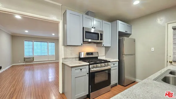 a kitchen with stainless steel appliances kitchen island granite countertop a stove a sink and a refrigerator