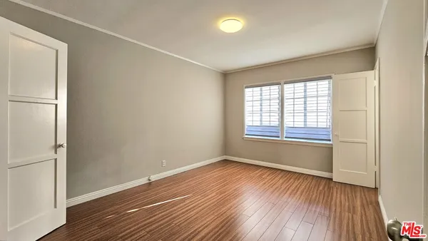 a view of an empty room with wooden floor and a window