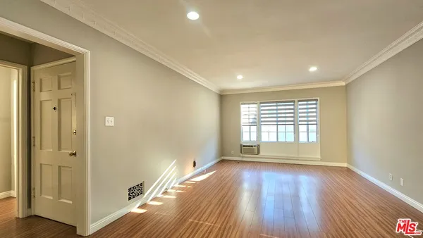 a view of an empty room with wooden floor and a window