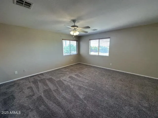 an empty room with windows and fan