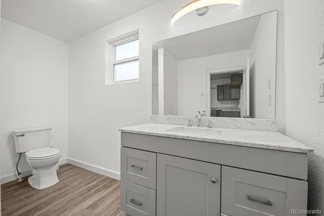 a bathroom with a granite countertop toilet sink and mirror
