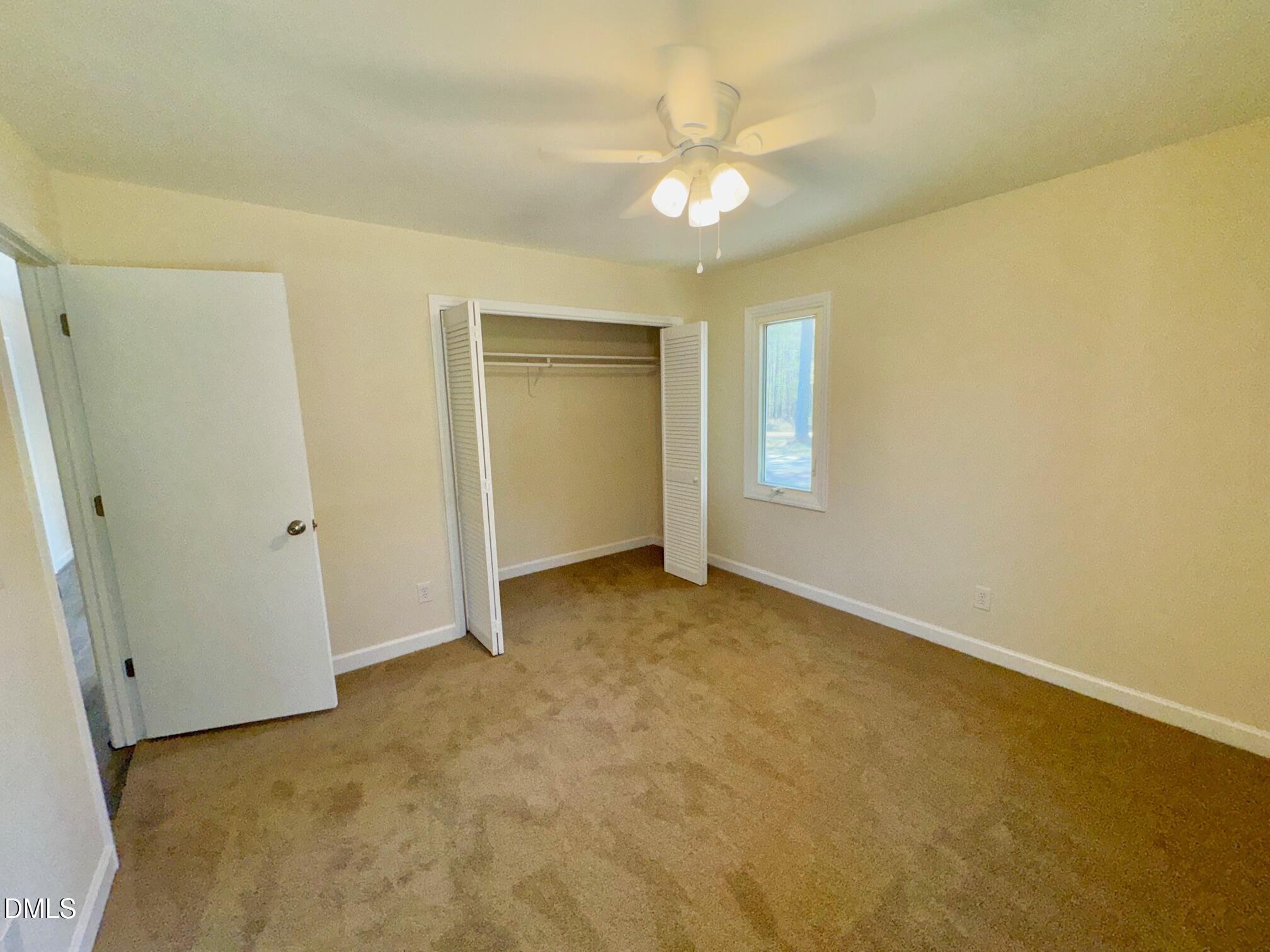 1720 Ross Mill Road Henderson, NC 27537 - Photo 29 of 42 an empty room with a chandelier fan and windows