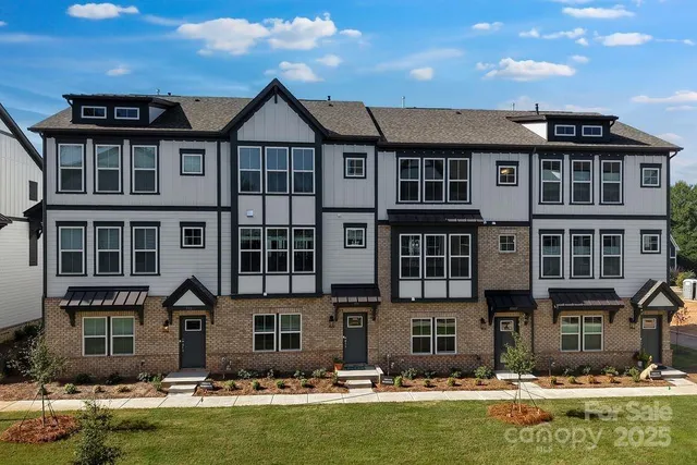 a front view of a residential apartment building with a yard and swimming pool