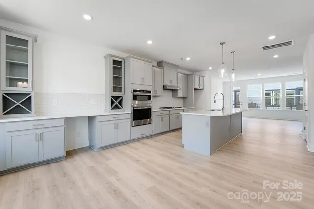 a large kitchen with stainless steel appliances kitchen island a large counter top and a wooden floors
