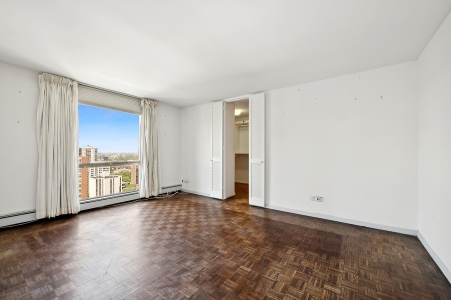 1310 North Ritchie Court, Unit 27B Chicago, IL 60610 - Photo 8 of 31 an empty room with wooden floor and windows