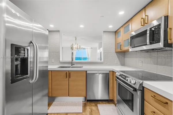 a kitchen with stainless steel appliances granite countertop a sink and a stove top oven with wooden floor