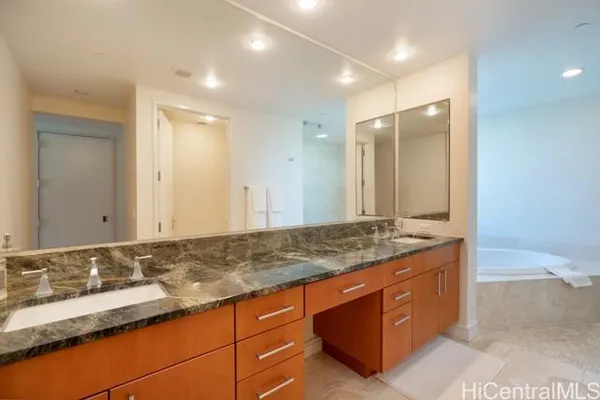 a bathroom with a granite countertop double vanity sink and mirror