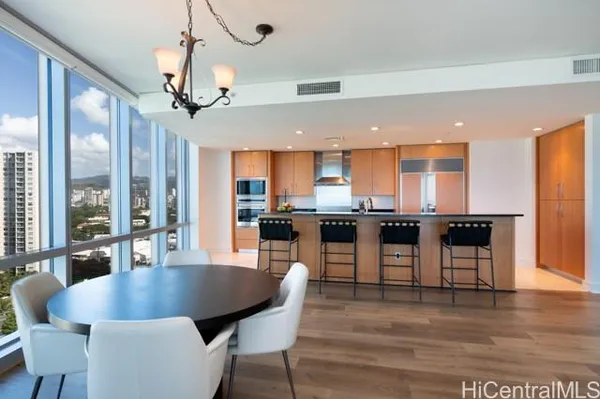 a dining room with furniture wooden floor and a kitchen view
