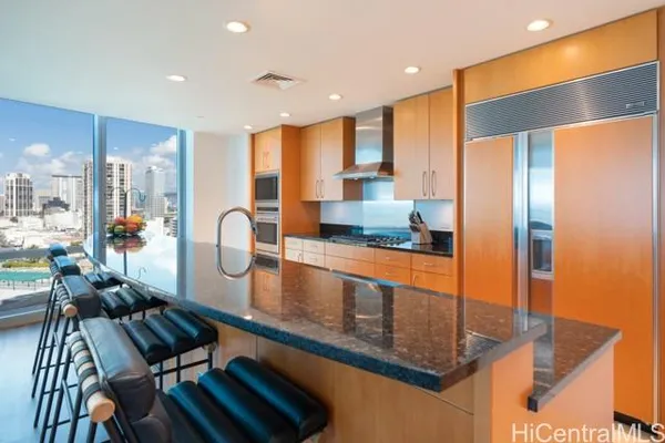 a kitchen with stainless steel appliances granite countertop a refrigerator a oven and a view of living room