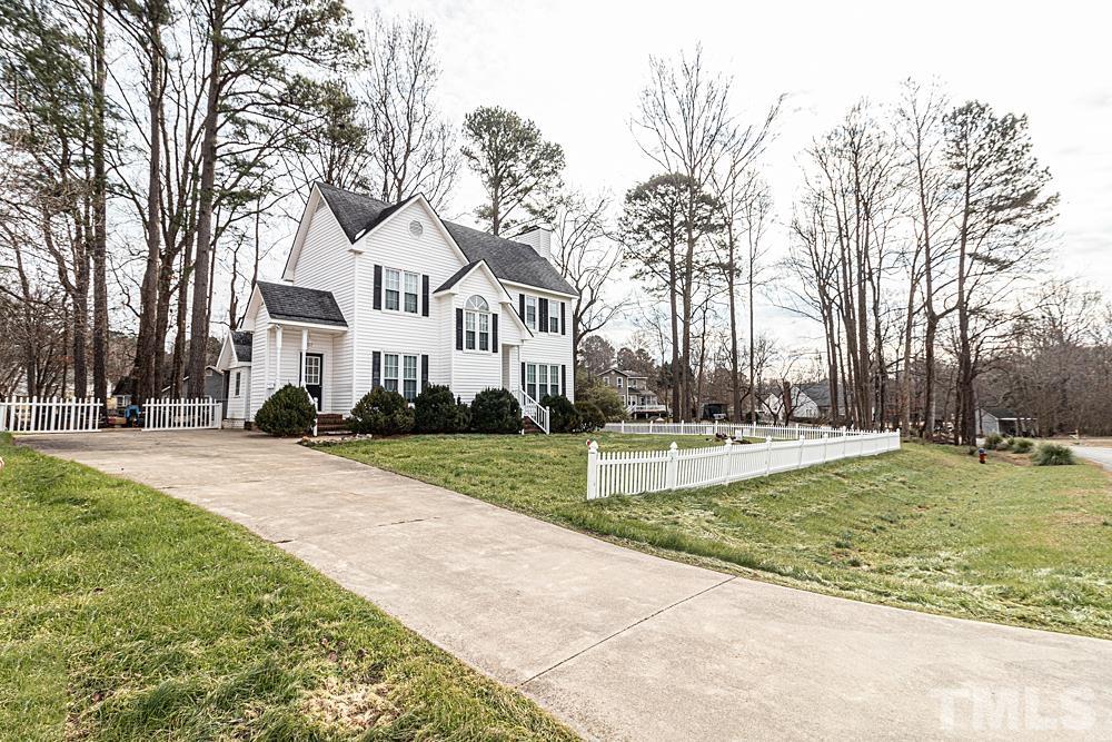 a view of a white house with a big yard and large trees