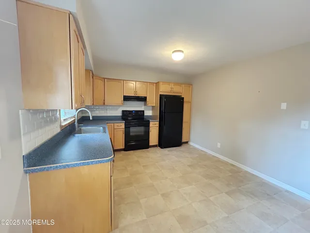 a kitchen with stainless steel appliances granite countertop a sink a stove a refrigerator a washer and dryer