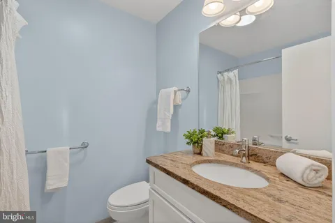 a bathroom with a granite countertop sink a toilet and a mirror