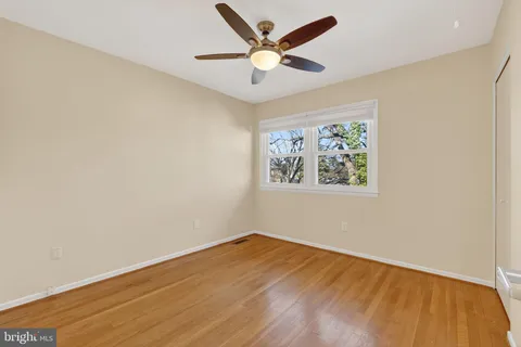 an empty room with wooden floor and ceiling fan