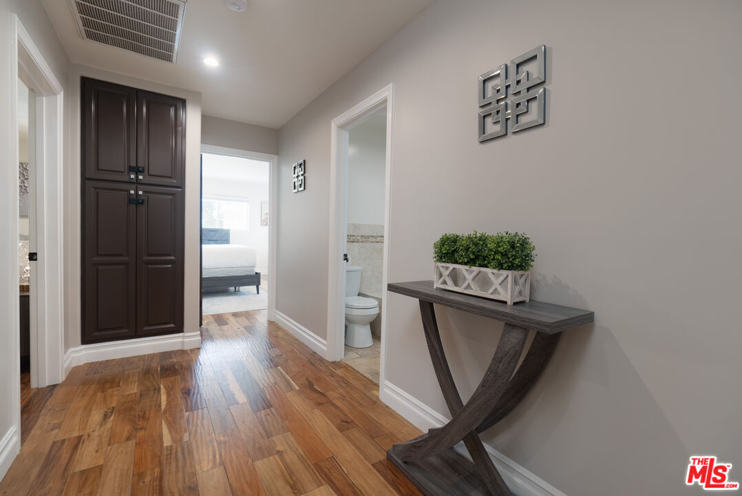 5181 Densmore Avenue Encino, CA 91436 - Photo 52 of 73 a view of a hallway to a room with wooden floor and furniture