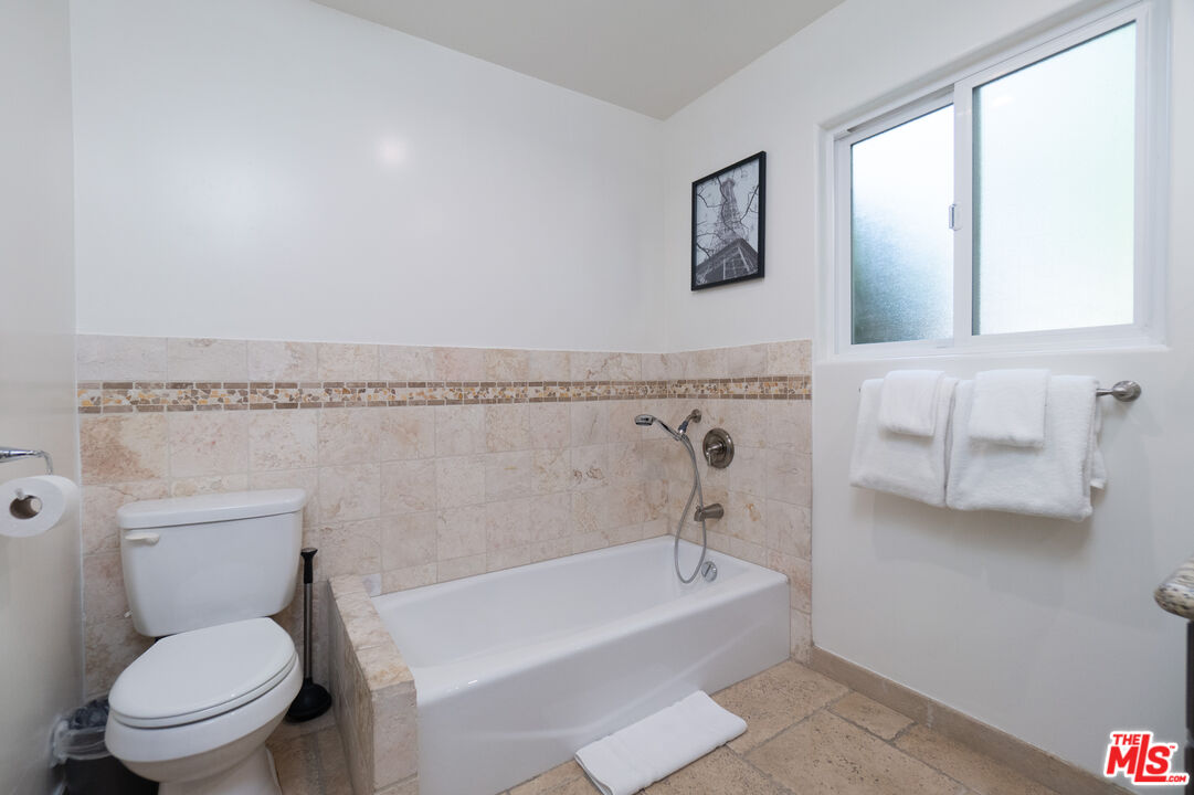 5181 Densmore Avenue Encino, CA 91436 - Photo 54 of 73 a bathroom with a granite countertop toilet a sink and bathtub
