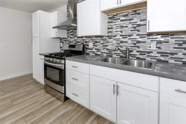 a kitchen with stainless steel appliances granite countertop a stove a sink and white cabinets