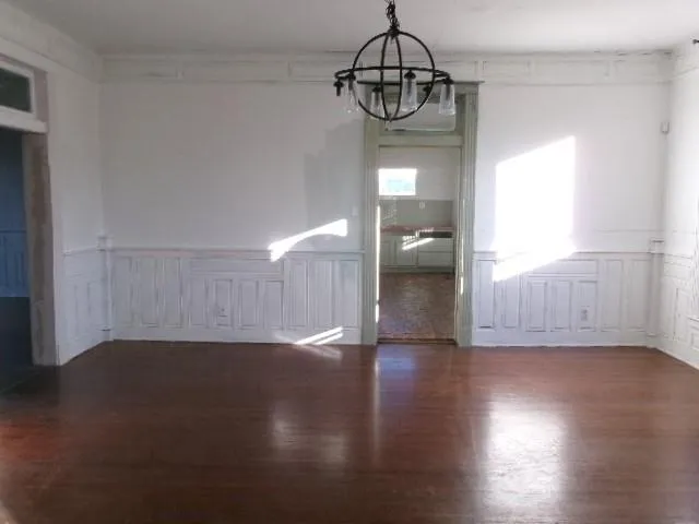 a view of a room with wooden floor chandelier and windows