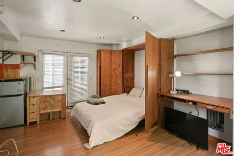 a bedroom with a bed wooden floor and window