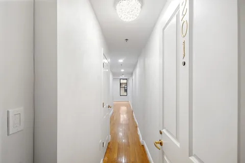 a view of a hallway with wooden floor and a chandelier