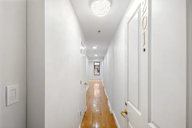 a view of a hallway with wooden floor and a chandelier