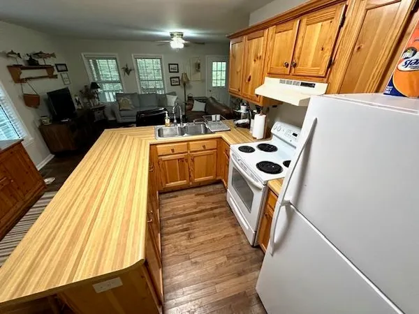 a kitchen with a refrigerator a stove a sink dishwasher and wooden cabinets with wooden floor