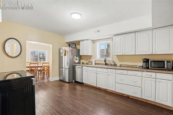 a kitchen with granite countertop a stove a sink a refrigerator and wooden cabinets