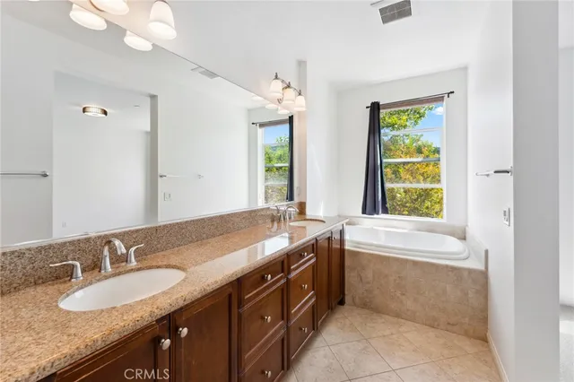 a bathroom with a granite countertop tub a double vanity sink and a large mirror