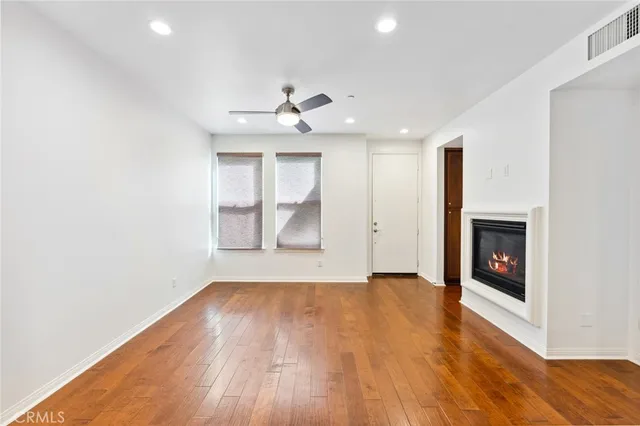 an empty room with wooden floor fireplace and windows