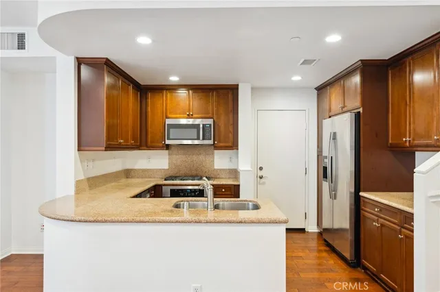 a kitchen with stainless steel appliances granite countertop a refrigerator a stove and a sink