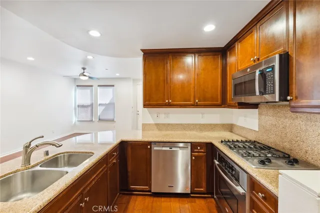 a kitchen with granite countertop a sink stainless steel appliances and cabinets