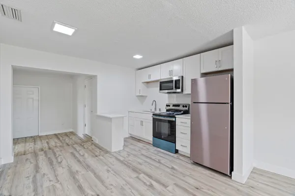a kitchen with granite countertop a refrigerator stove and wooden floor