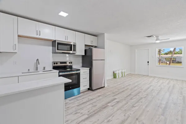 a kitchen with a refrigerator cabinets and wooden floor
