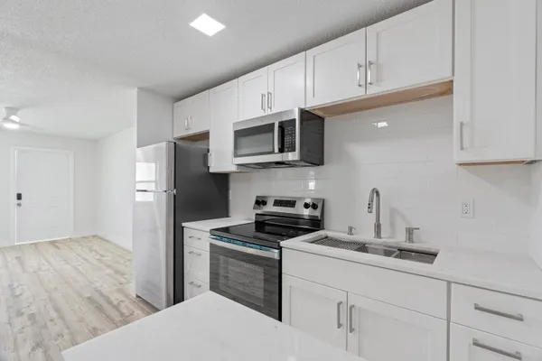 a kitchen with stainless steel appliances a sink a stove a microwave a refrigerator a sink and cabinets