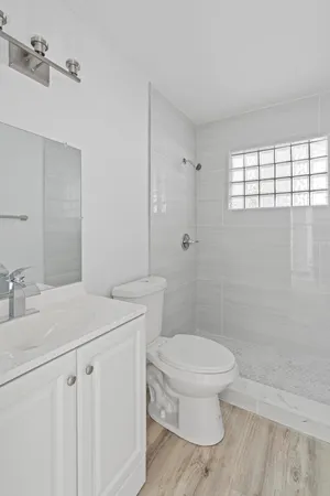 a bathroom with a granite countertop sink a toilet a mirror and shower