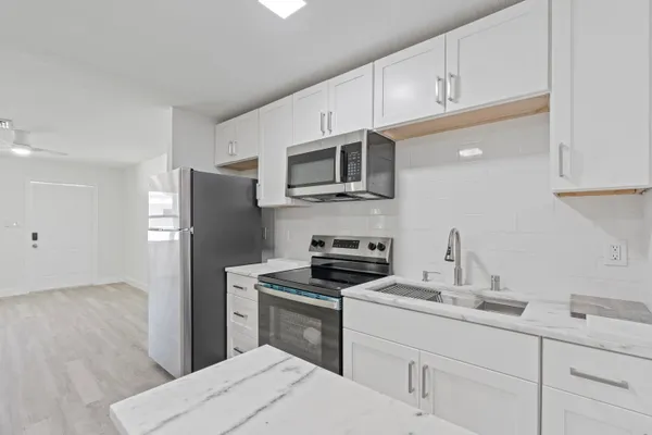 a kitchen with refrigerator a microwave a sink and cabinets
