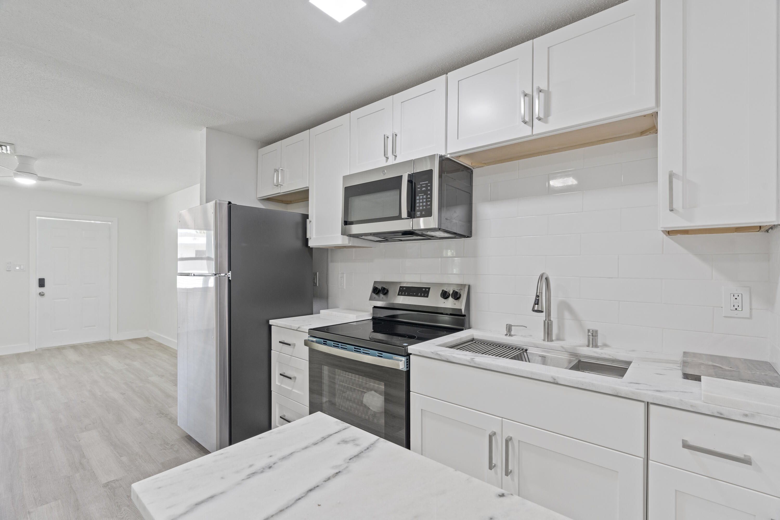 662 Granada Street Fort Pierce, FL 34949 - Photo 40 of 48 a kitchen with refrigerator a microwave a sink and cabinets