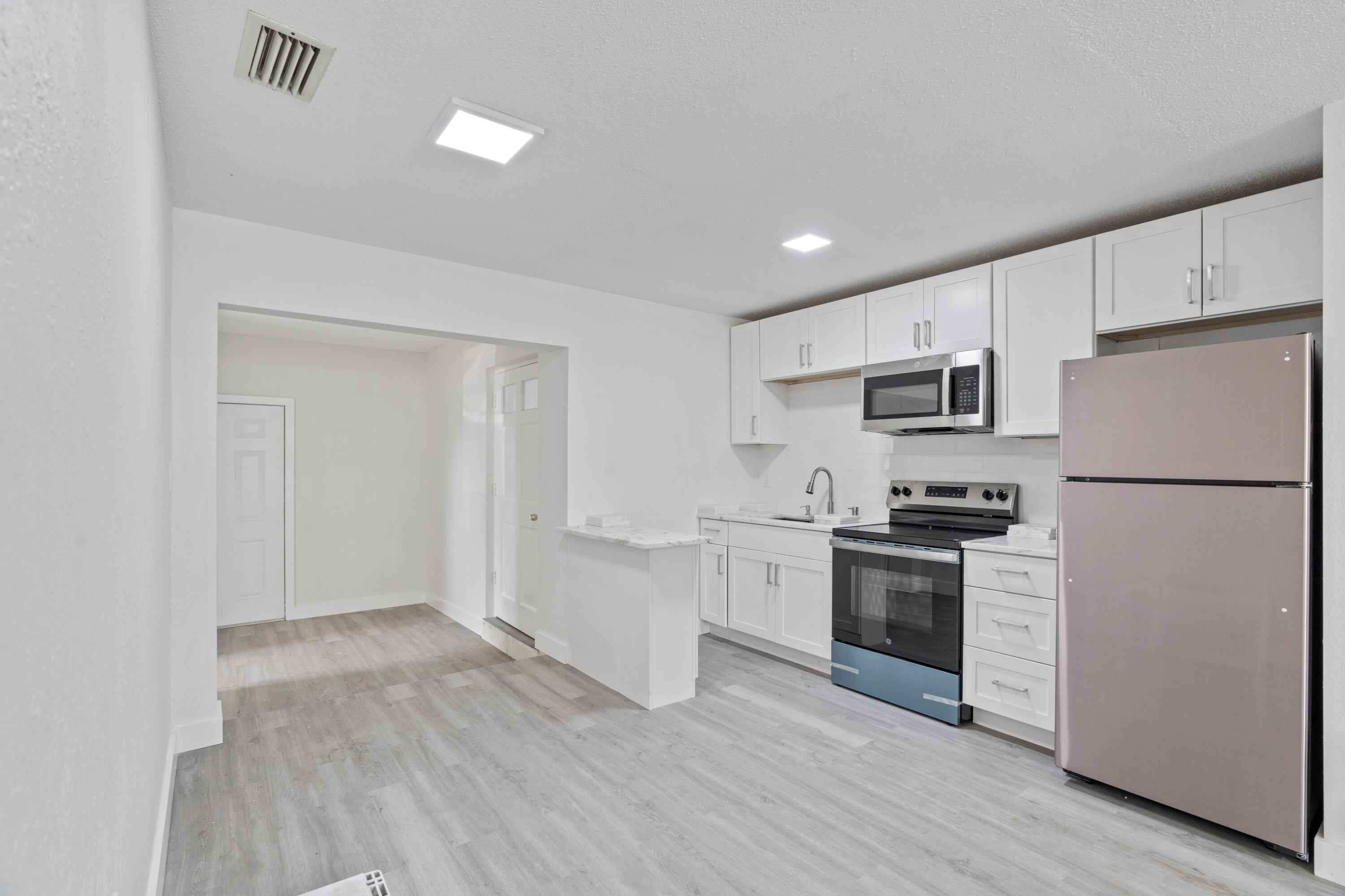 662 Granada Street Fort Pierce, FL 34949 - Photo 44 of 48 a kitchen with stainless steel appliances granite countertop a refrigerator a stove a sink dishwasher and white cabinets with wooden floor