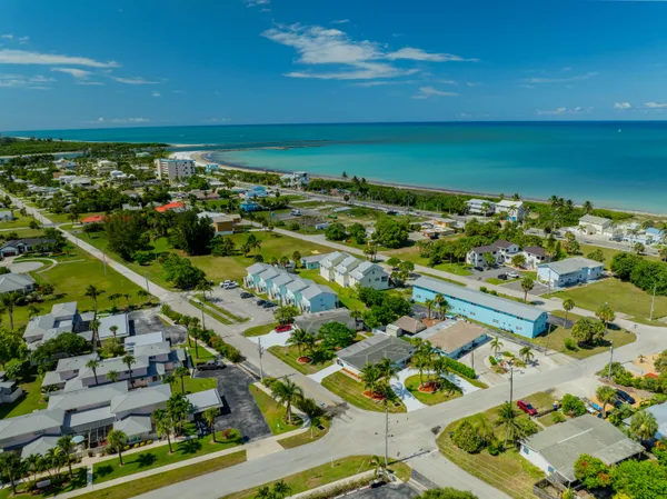 an aerial view of a city with lots of residential buildings ocean and mountain view in back