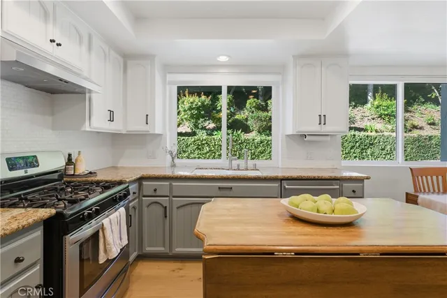 a kitchen with kitchen island granite countertop a sink a counter top space and stainless steel appliances