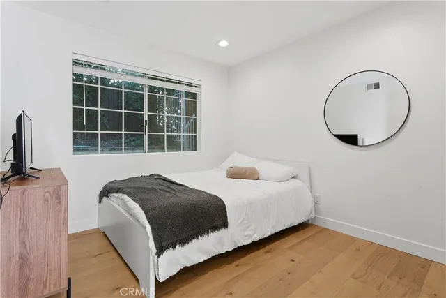 a bedroom with a bed a mirror and a window